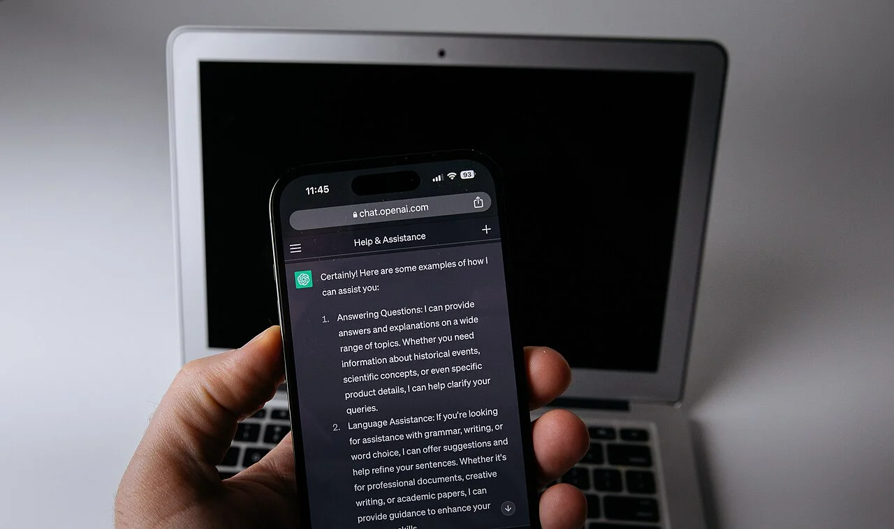 Смартфон с приложением ChatGPT рядом с ноутбуком