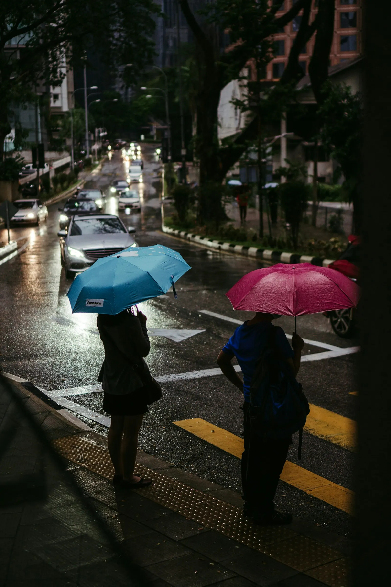 Orang ramai berjalan dengan payung di kaki lima pada hari hujan di Kuala Lumpur