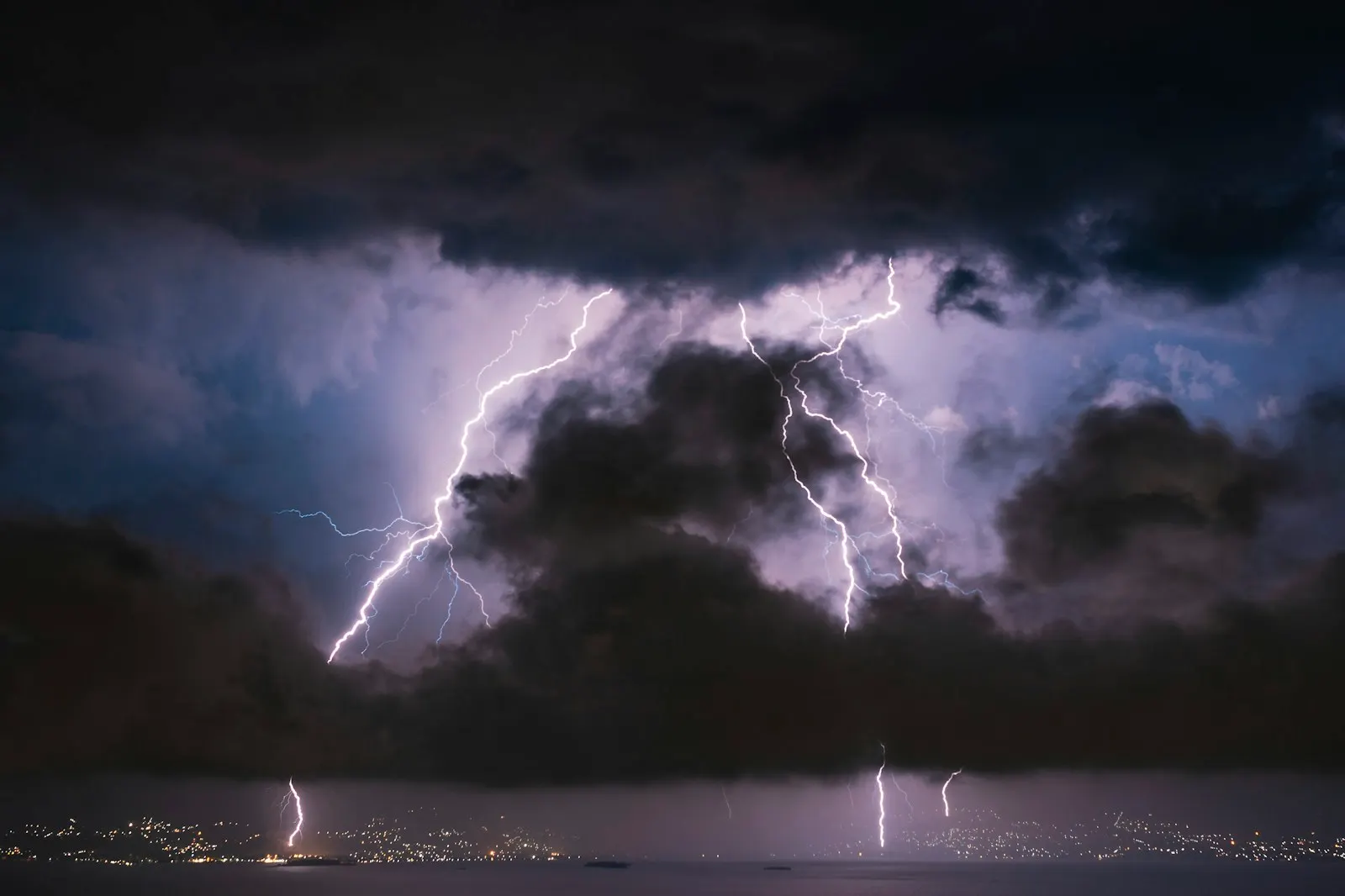Lightning flashing behind storm clouds above a city skyline