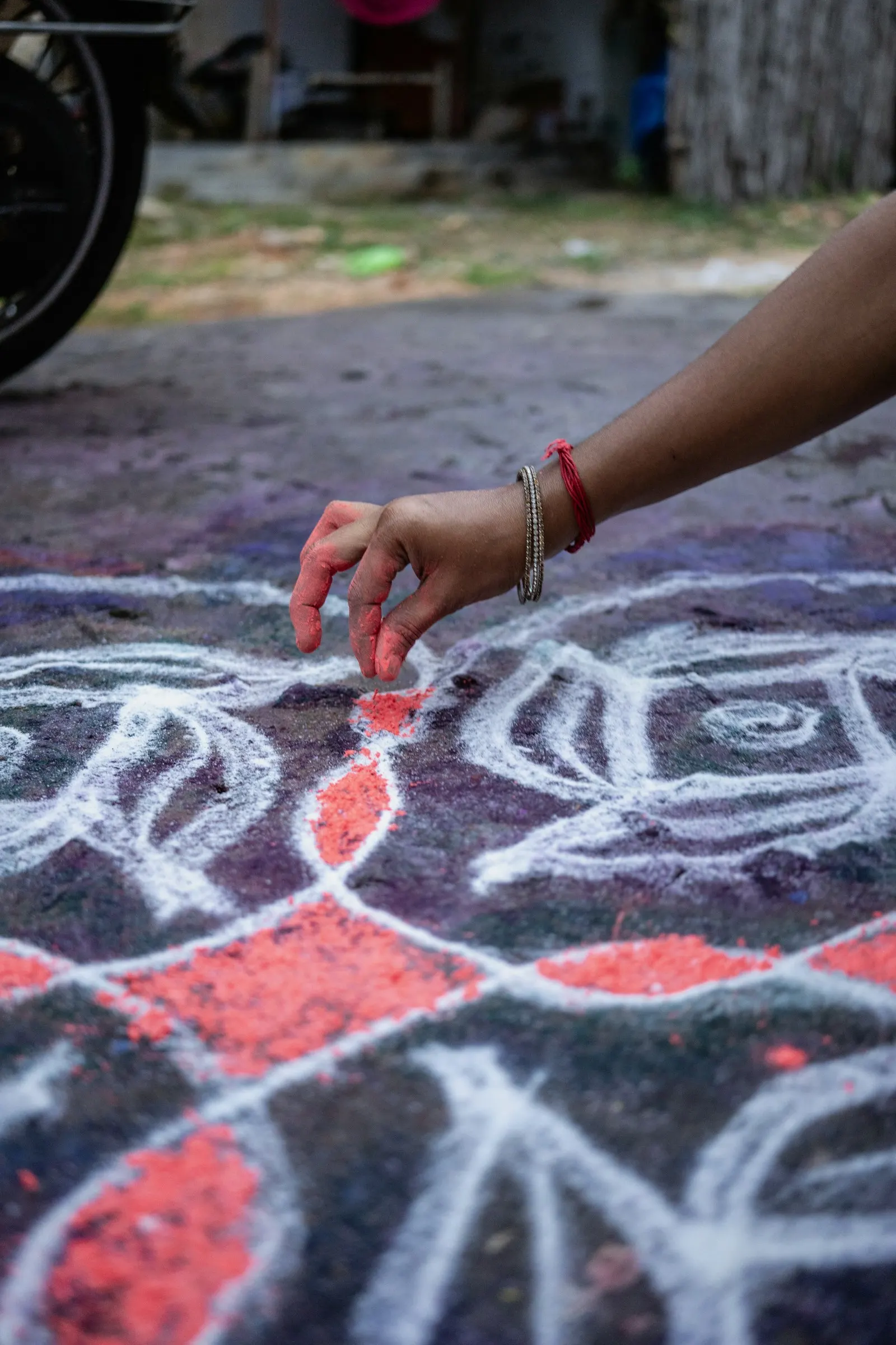 Hands drawing a kolam pattern on the ground
