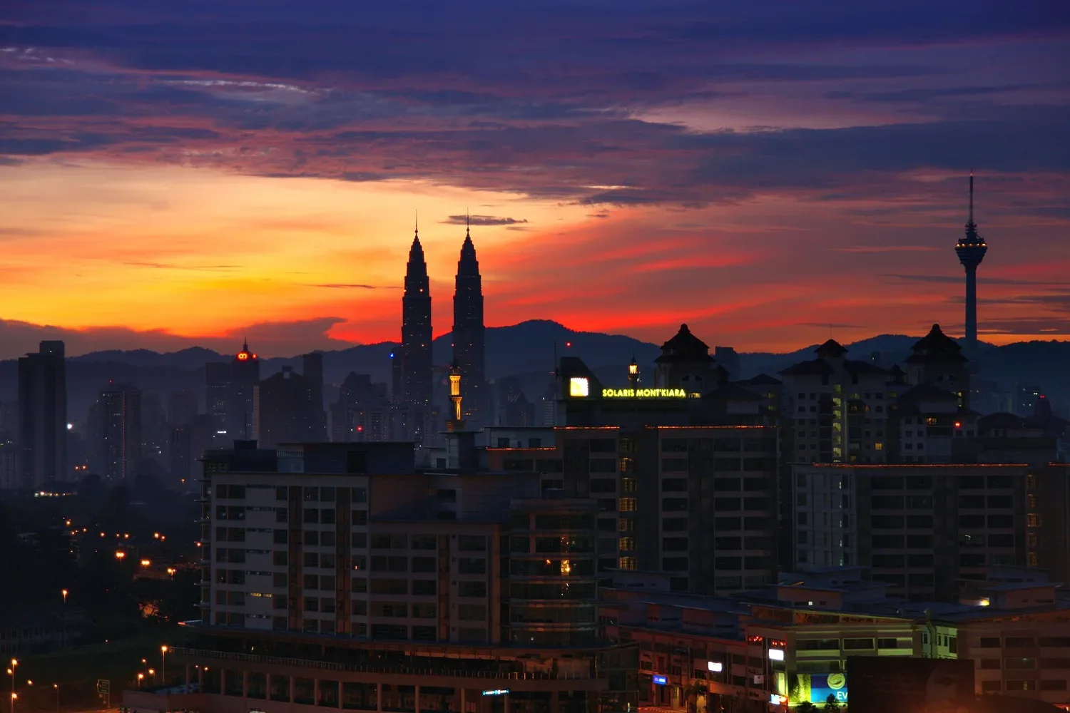 Langit subuh berwarna oren dan ungu di belakang Menara Berkembar Petronas dan Menara KL, Kuala Lumpur
