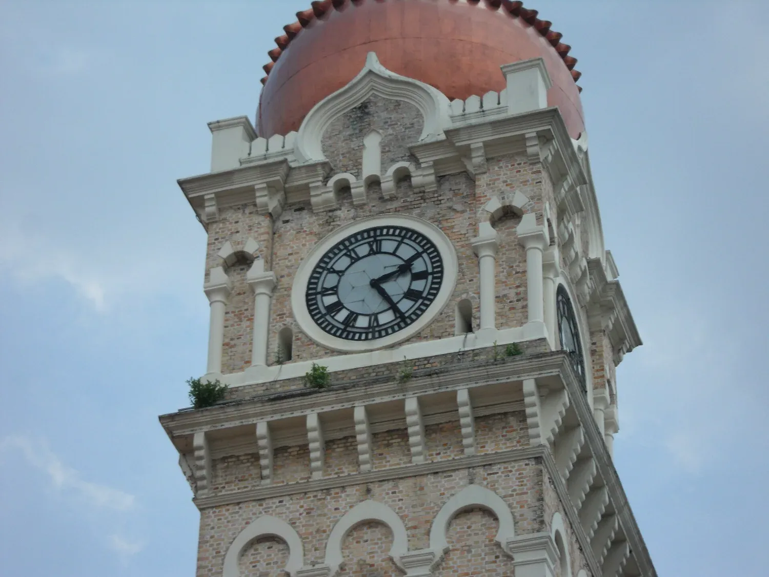 Menara jam Bangunan Sultan Abdul Samad di Kuala Lumpur dari dekat, dengan langit biru di belakang